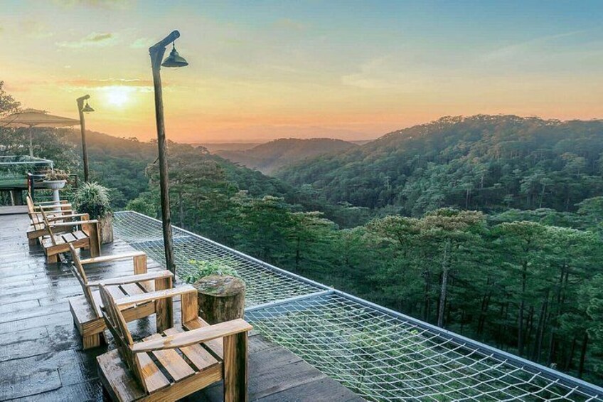 A wooden deck with chairs overlooking a forested valley at sunset. 3