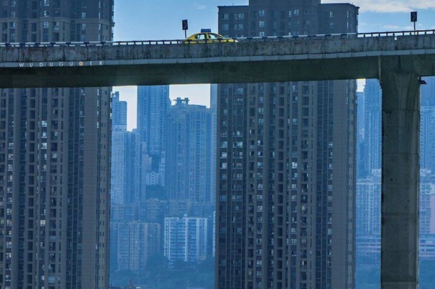 Een gele taxi op een brug, met hoogbouw op de achtergrond. 3
