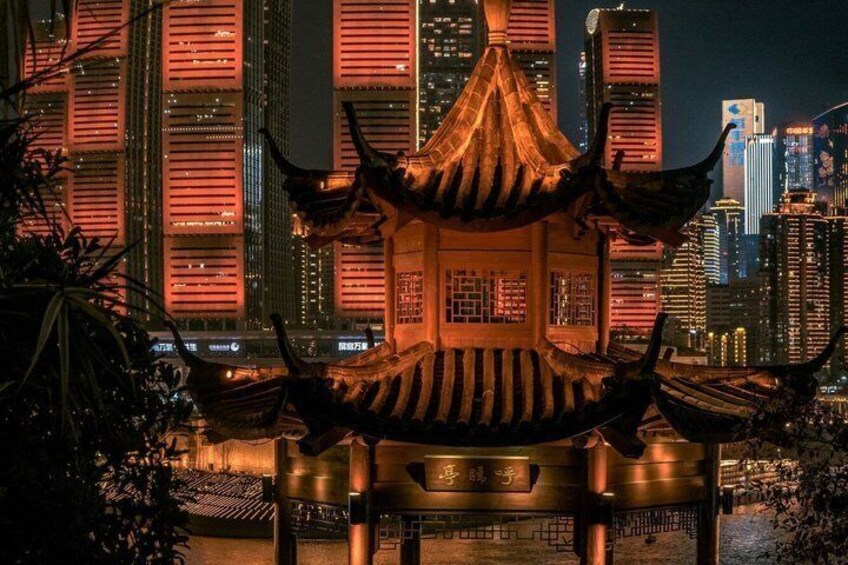 Een traditioneel Chinees paviljoen met pannendak, met op de achtergrond een modern stadsbeeld bij nacht. 4