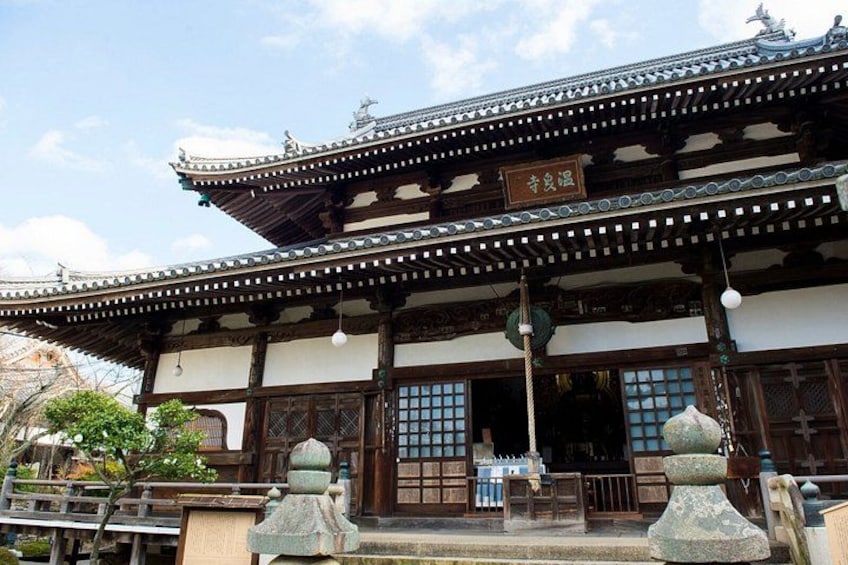 Ein traditionelles japanisches Gebäude mit einem Ziegeldach, Holzbalken und einem Schild. 5