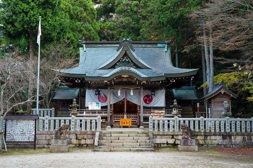 Ein traditioneller japanischer Tempel mit einem gewölbten Dach, einem hölzernen Tor und steinernen Stufen, die zum Eingang führen. 4