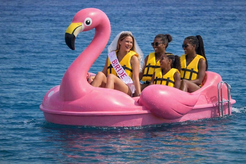 A pink inflatable flamingo boat with people wearing life vests and a 'BRIDE' sash. 2