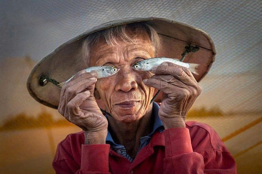 Una persona tiene un pesce vicino al volto. 1