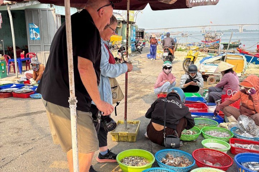 Persone in un mercato con diversi cesti colorati di pesce. 3