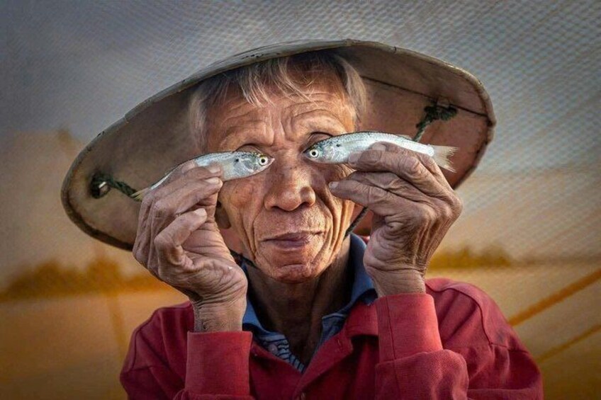 A person holding two fish in front of their face. 1