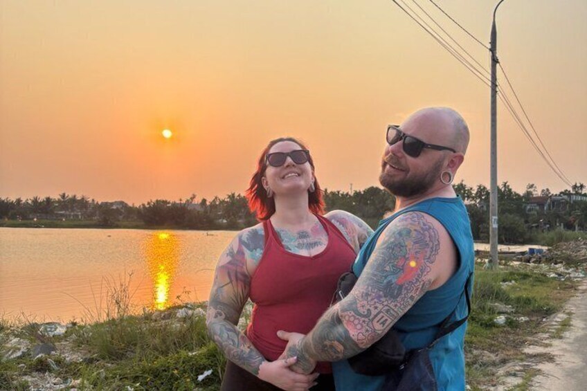 Two people standing by a lake at sunset. 4
