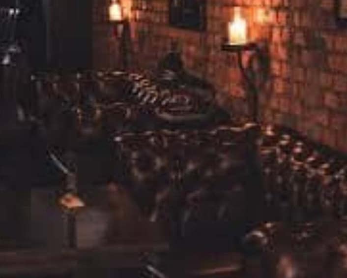 A dimly lit room with a leather sofa, a table, and candles on the wall. 4