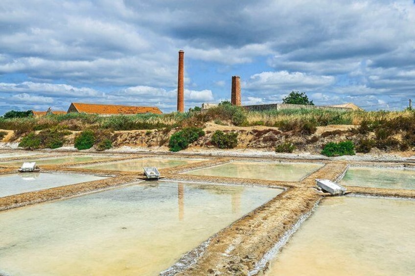 Un paysage composé de champs de sel en terrasses et, au loin, de deux cheminées en briques. 1