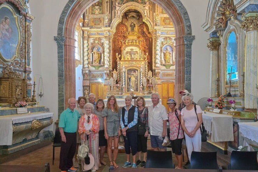 A group of people inside a church with ornate altars and religious statues. 2