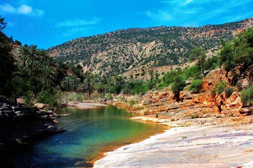 A river with clear water, surrounded by rocky terrain and sparse vegetation. 1