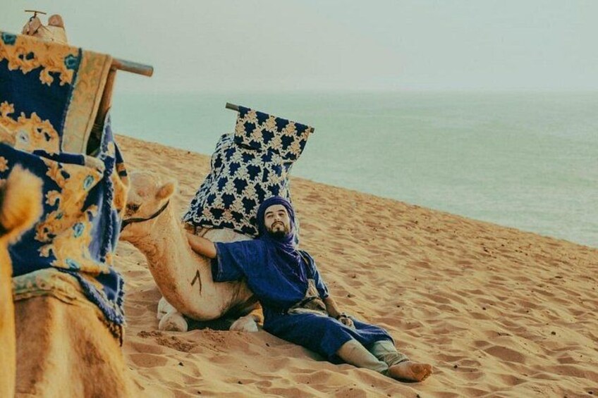 A person lying on a camel in a desert setting. 5
