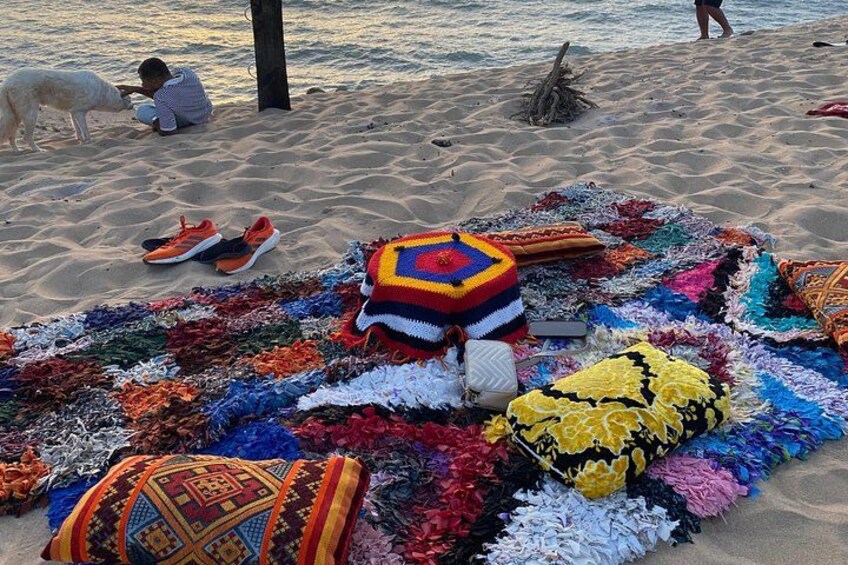 A beach with colorful blankets and a dog. 2