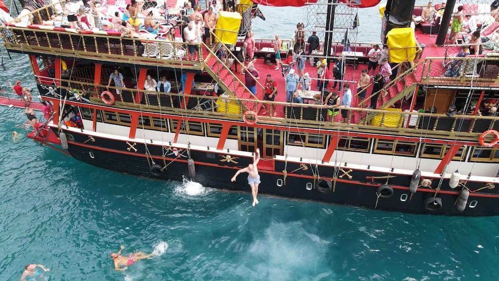 A large boat with people on deck and some in the water. 5