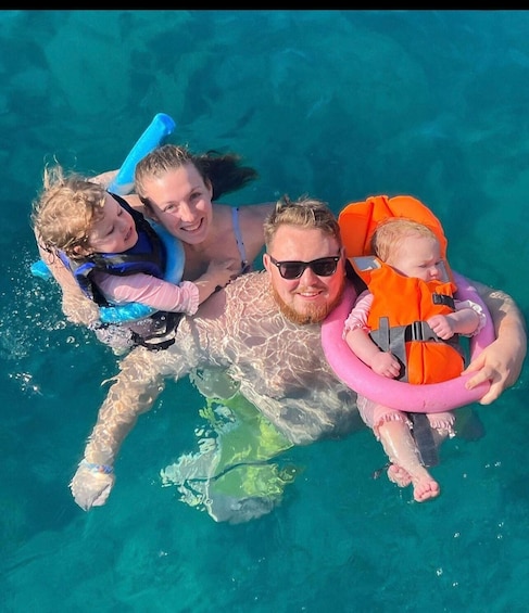 A person floating in a pool with a dog and two children. 2