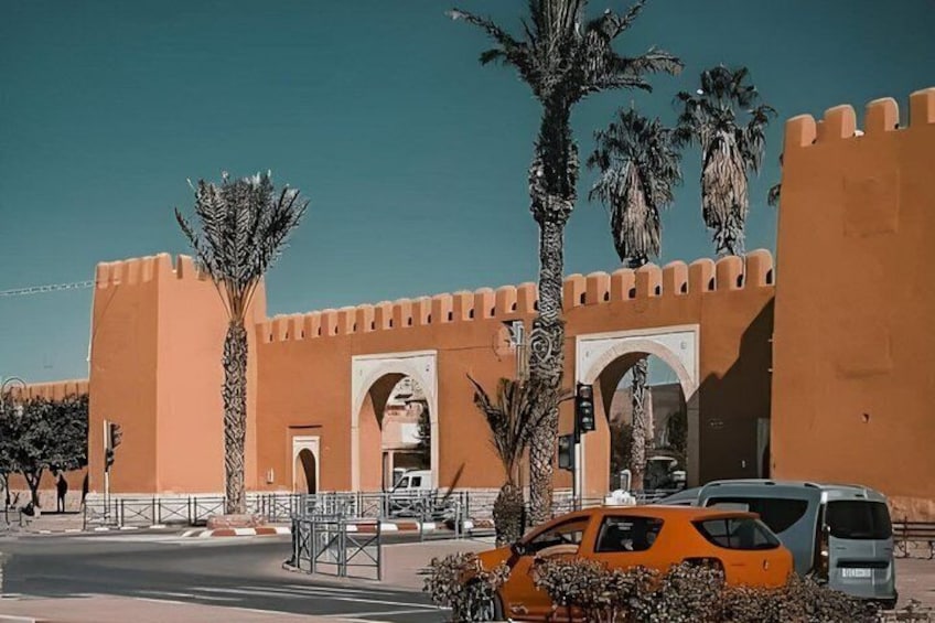 A building with a large archway, palm trees, and parked vehicles. 2