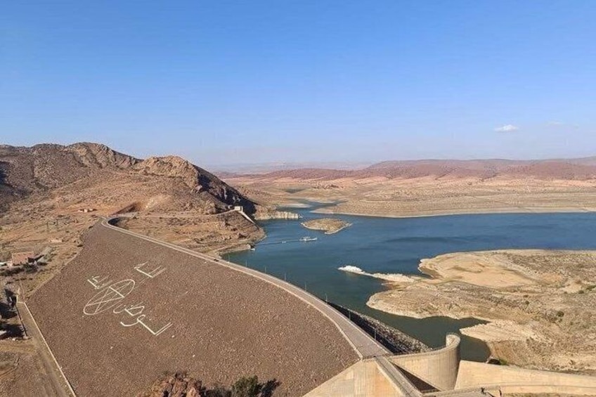 A dam with a river flowing through it, surrounded by arid hills. 3