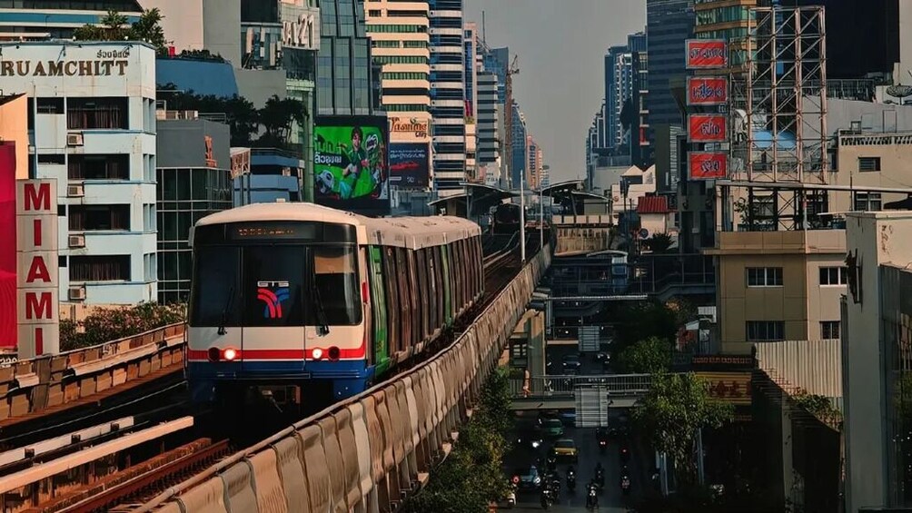 A train on an elevated track in an urban setting with buildings and billboards. 2