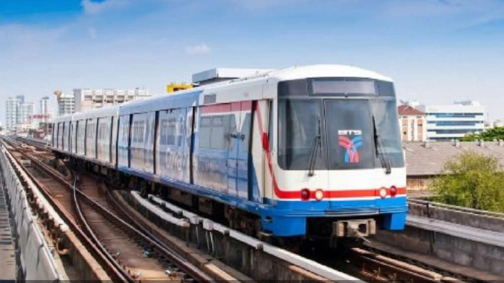 A modern train on tracks with a cityscape in the background. 4