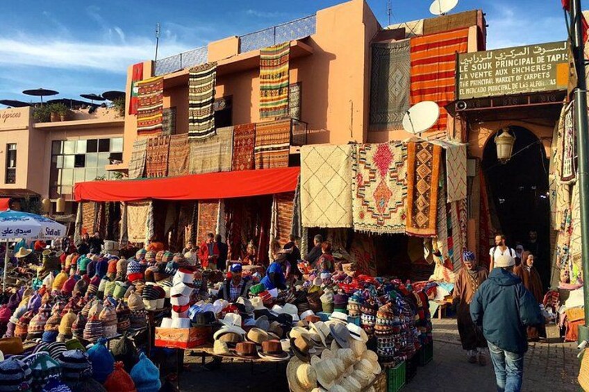 A bustling outdoor market with colorful textiles and various goods displayed. 1