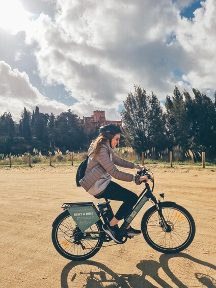 A person riding a bicycle on a dirt path with a castle in the background. 2