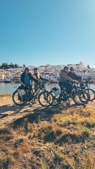 Three people on bicycles by a waterfront with buildings in the background. 5