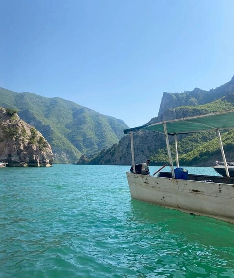 A boat anchored near a mountainous coastline with clear turquoise water. 5