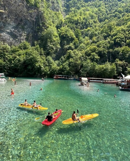 People kayaking on a clear river surrounded by lush greenery. 3