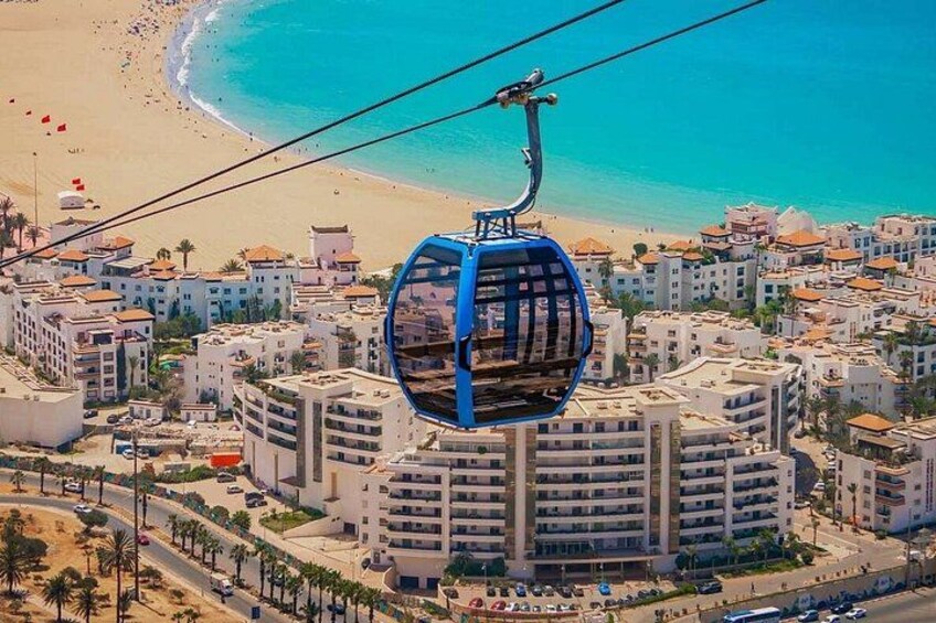 A cable car over a coastal city with buildings and a beach. 2