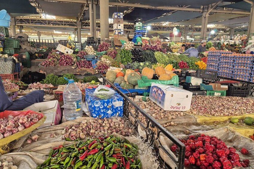 A bustling indoor market with various vegetables and fruits on display. 5