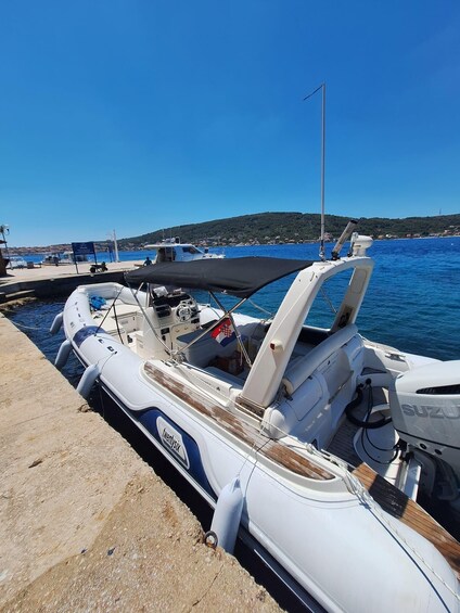 A white boat docked at a marina with a clear blue sky and a hilly landscape in the background. 2