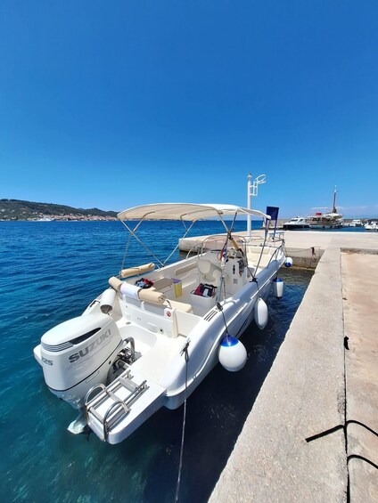 A white motorboat docked at a pier with a clear blue sky and calm sea. 4