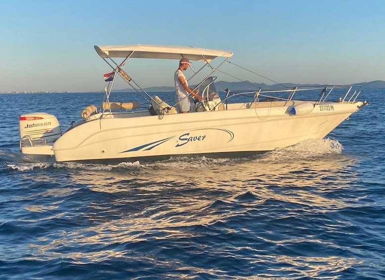 A white speedboat with 'Sauer' branding and a 'Johnson' outboard motor, sailing on open water. 4