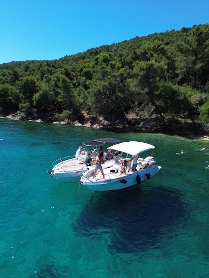 Two boats on a clear turquoise sea with a forested hill in the background. 3
