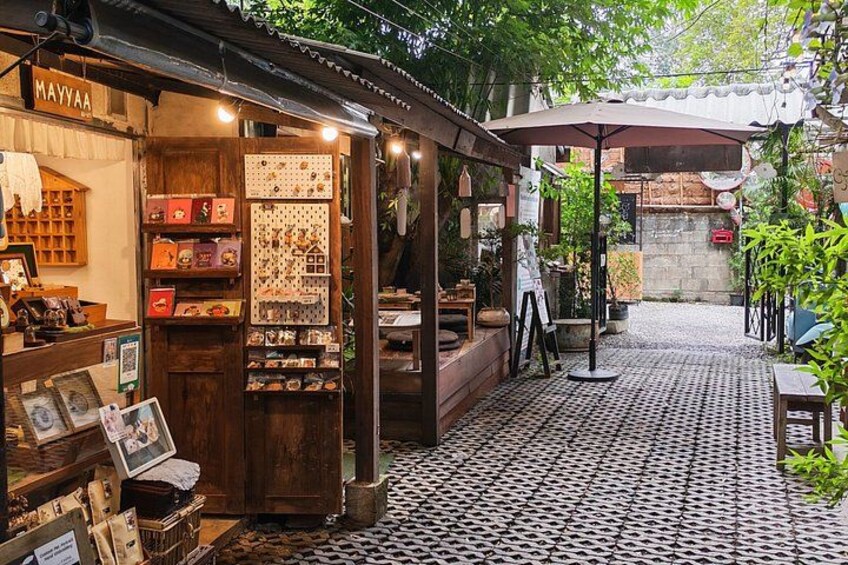 A cozy outdoor café with a tiled floor, wooden furniture, and a variety of food and drink items displayed. 4