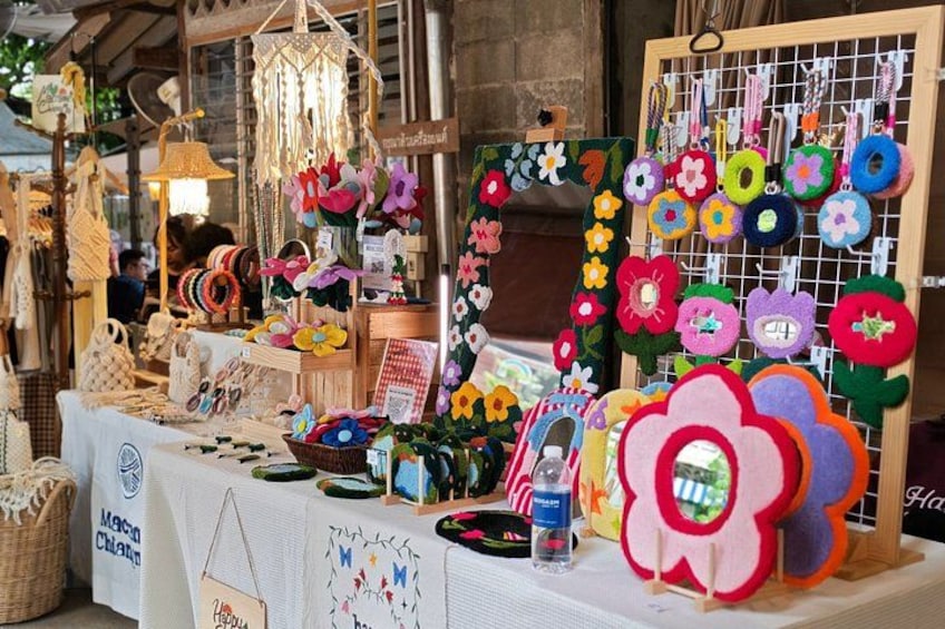 A craft market stall with handmade items, including felt flowers and woven baskets. 2