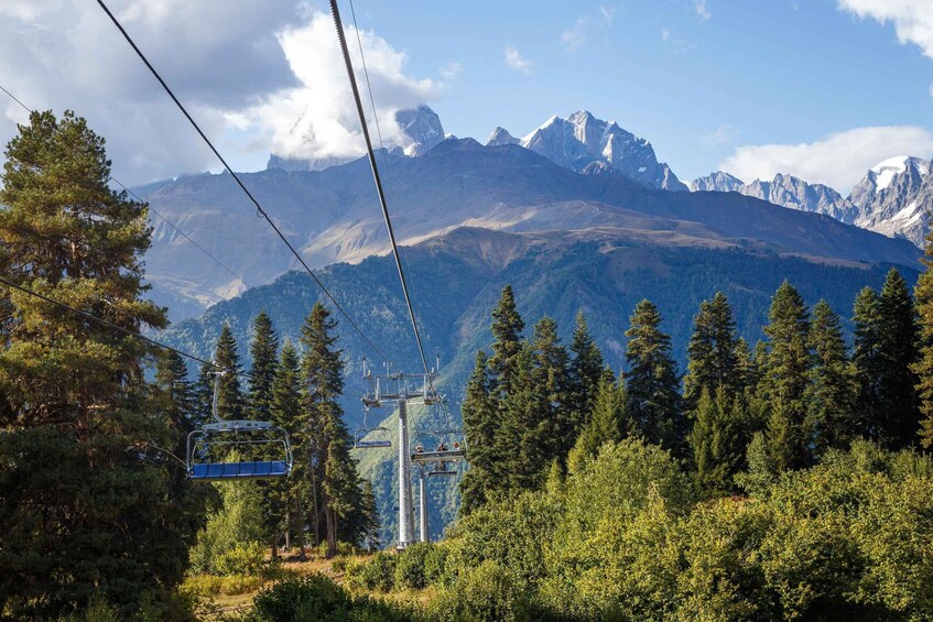 A mountain landscape with a ski lift, trees, and snow-capped peaks. 2