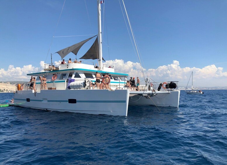 A white sailboat with people on deck, another smaller boat nearby, and a coastline in the background. 5