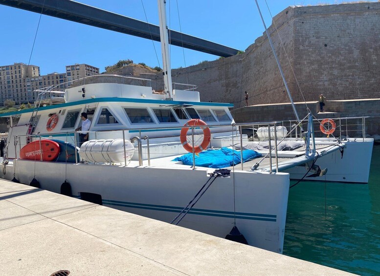 A white boat docked at a pier with lifebuoys and a blue cover on the deck. 3