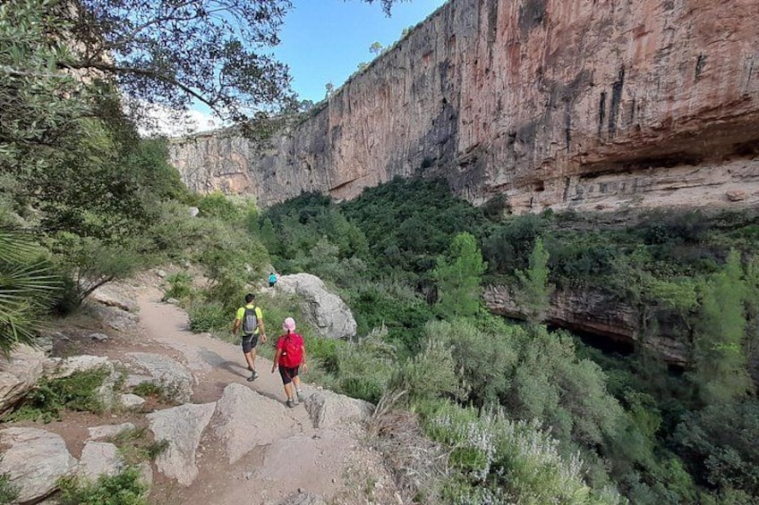Hikers on a rocky trail with a canyon in the background. 1