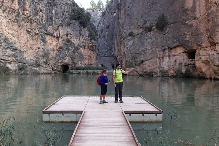 A wooden dock extending into a calm river surrounded by rocky cliffs. 3