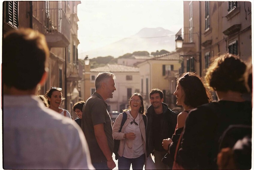 A group of people walking on a street with buildings and a mountain in the background. 5