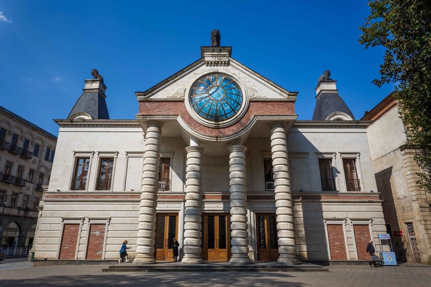 A historic building with a large clock, columns, and a statue on top. 2