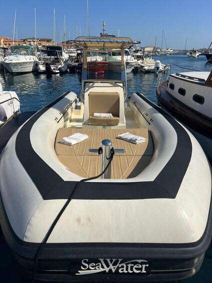 A boat docked at a marina with other boats, a clear sky, and a calm sea. 1