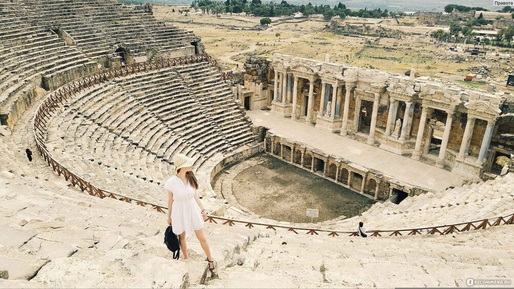 An ancient amphitheater with stone steps and columns, surrounded by ruins and trees. 5
