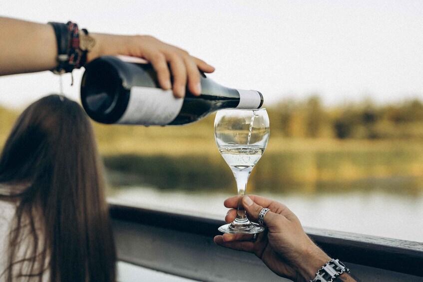 A person pouring wine into a glass held by another person. 1