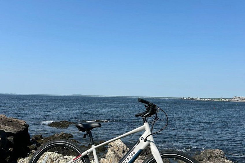 A bicycle parked on rocks by the sea with a clear sky. 4