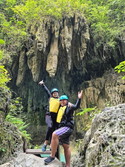 Two people on a rock ledge with a cave-like rock formation in the background. 3