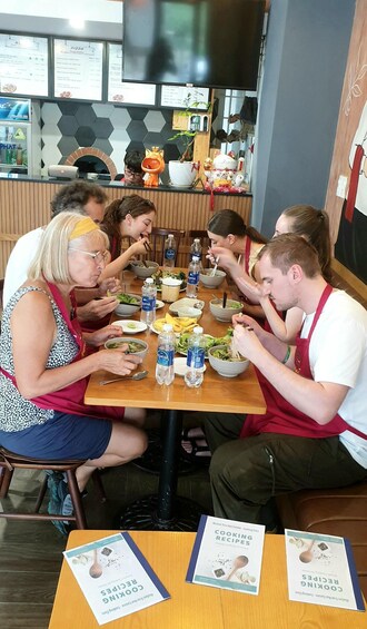 A group of people dining at a restaurant with a menu board and a pizza oven in the background. 3