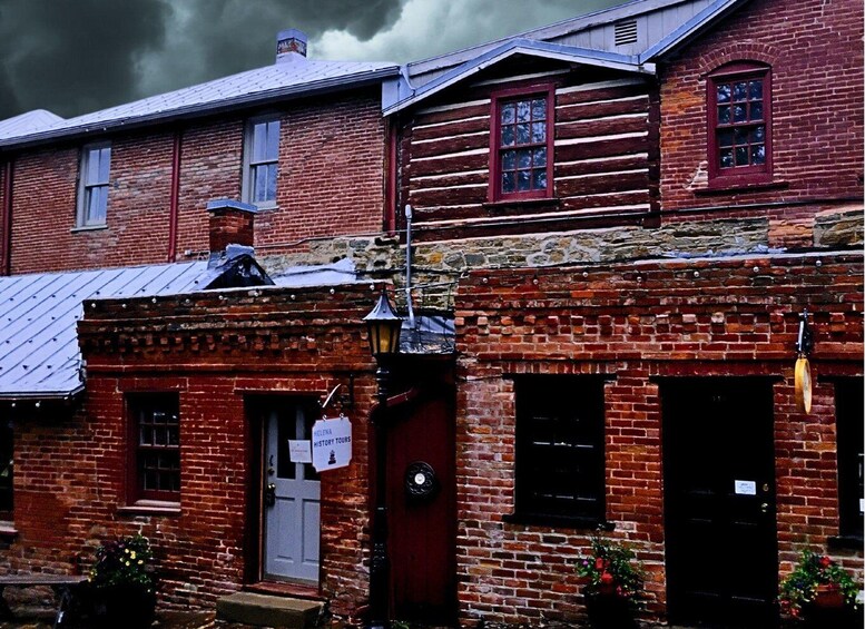A historic brick building with a red door, a sign for history tours, and a stormy sky. 3