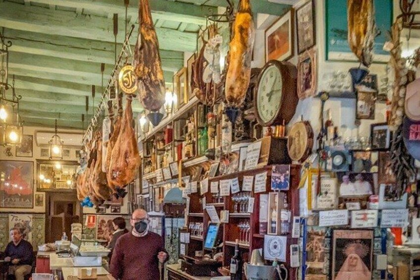 A cluttered shop with hanging meat products, clocks, and various items on shelves. 3